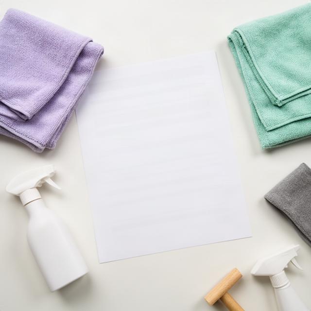 Printed room-by-room cleaning checklist beside folded cloths and professional cleaning supplies